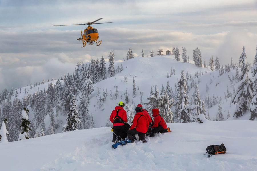 helicopter above snow and rescue workers